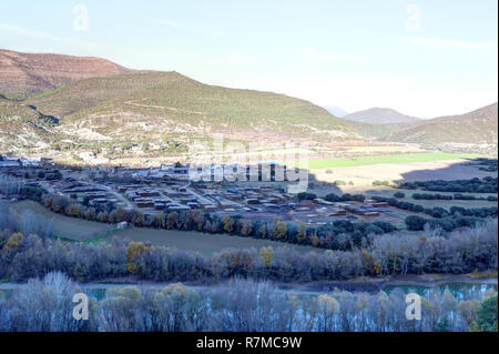 Un paesaggio di montagne rocciose e campi di raccolto con Santa Maria y la Peña cittadina rurale, come visto da Mallos de Riglos, nei Pirenei, Aragona, Spagna Foto Stock