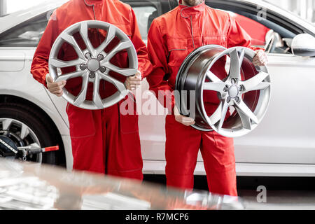 Ritratto di due auto meccanica in rosso uniforme con ruote in lega al servizio auto. Immagine ritagliata con nessun volto Foto Stock