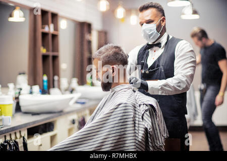 Hipster uomo client haidresser visita e un parrucchiere in un barbiere. Foto Stock