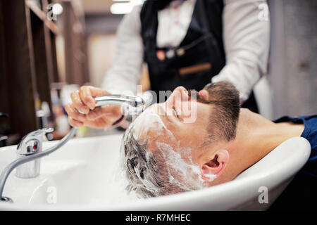 Hipster uomo client haidresser visita e un parrucchiere in un barbiere. Foto Stock