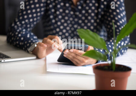 Giovani indiani impiegato femminile tenendo il telefono in mano vicino fino Foto Stock