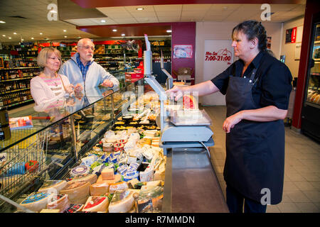 Shop assistant che serve una coppia senior presso il contatore di formaggio, acquisti in un supermercato, Germania Foto Stock