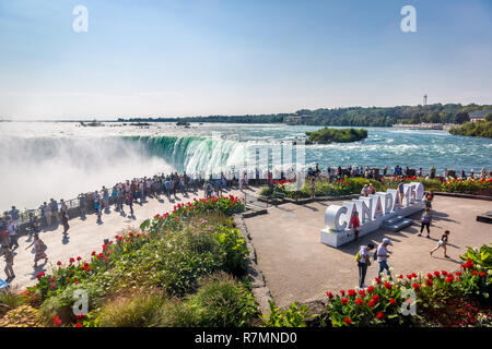 Niagara e Canada - Sep 10th 2017 - grande gruppo di turisti in cerca di cascate del Niagara con la " Canada 150 anni di firmare in un cielo blu Giorno in Niagara Foto Stock