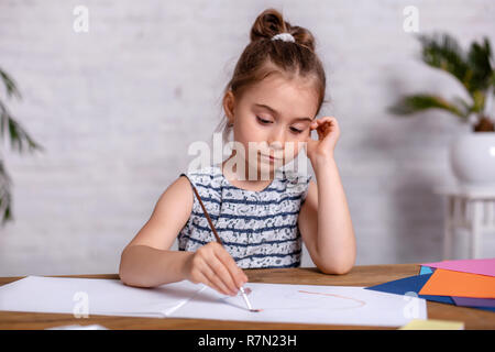 Ispirato bambina al tavolo disegnare con vernici Foto Stock