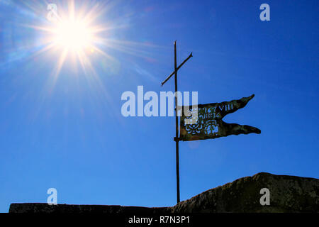 Bandiera di metallo sulla parte superiore della Fortezza di Montalcino la torre contro il cielo blu con sunburst, Val d'Orcia, Toscana, Italia. La fortezza fu costruita nel 1361 in cima th Foto Stock