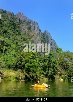 Tourist scendendo Nam Song River in un tubo circondato da paesaggi carsici in Vang Vieng, Laos. Il tubo è una popolare attività turistica in Vang Vieng. Foto Stock