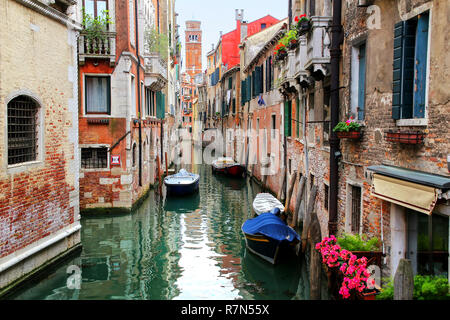 Case e barche lungo stretto canale a Venezia, Italia. Venezia si trova di fronte a un gruppo di 117 piccole isole che sono separate da canali e collegate b Foto Stock