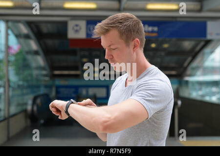 Bel giovane uomo turistico il controllo del tempo di fronte alla stazione ferroviaria di Bangkok Foto Stock