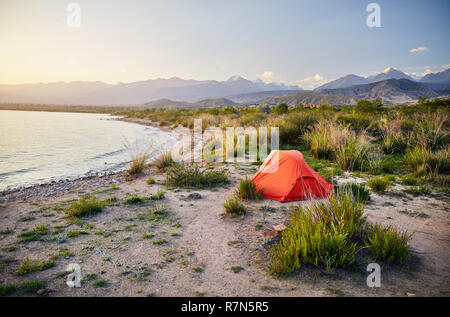 Tenda arancione sulla riva di Issyk Kul lago di montagna in Kirghizistan Foto Stock