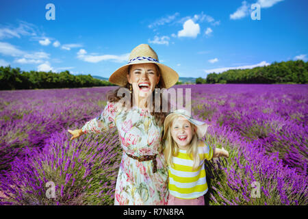 Felice giovane madre e figlia esultanza contro il campo di lavanda della Provenza, Francia. famiglia sono lieti che giunsero a Provenza. Vibrante fie di lavanda Foto Stock