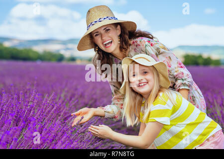 Ritratto di moda la madre e il bambino ad esplorare la lavanda contro campo di lavanda della Provenza, Francia. Ideale per la famiglia agriturismo con pittoresche pianure Foto Stock