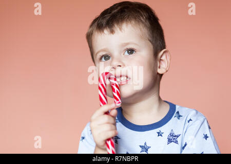 Un ragazzo simpatico mangiando caramelle bastoni. Rosso a strisce bianche Candy Cane Foto Stock