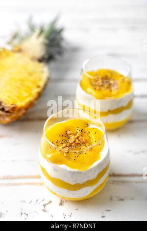 Colpo verticale di mango e ananas smoothie con yogurt in due bicchieri Foto Stock