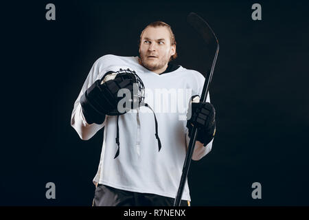 Bel giovane azienda mazza da hockey copre la bocca con la mano esprime la paura Foto Stock