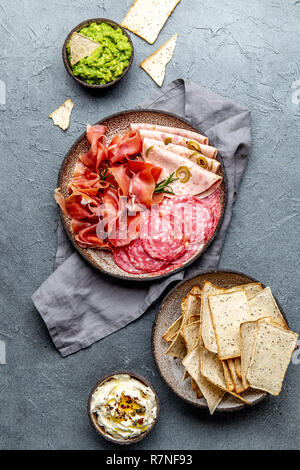 Antipasto. Piatto a base di carne, patatine e salse, vino rosso su sfondo grigio. Vista superiore Foto Stock