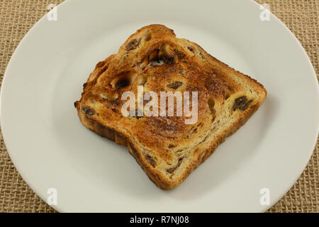 Close up di fetta di cannella imburrato raisin pane toast sulla piastra bianca Foto Stock