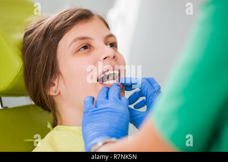 Dentista sta esaminando i denti di una bambina. Foto Stock