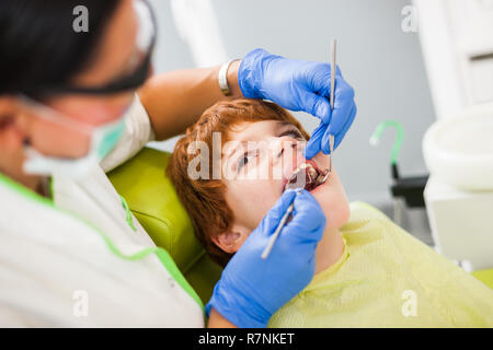 Dentista sta esaminando i denti di un ragazzo. Foto Stock