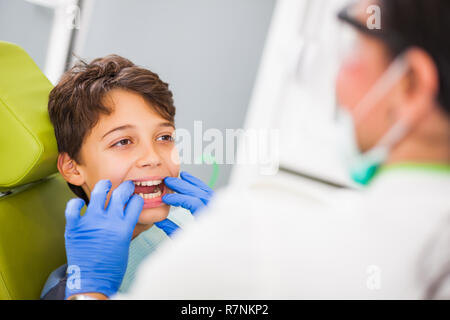 Dentista sta esaminando i denti di un ragazzo. Foto Stock