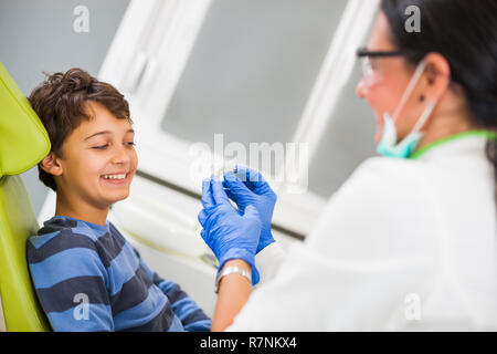 Dentista è insegnamento little boy circa le bretelle. Foto Stock