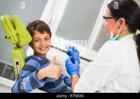 Dentista è insegnamento little boy circa le bretelle. Foto Stock