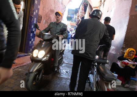 Strada trafficata scena di Marrakech con moto e donna di accattonaggio in strada, Marrakech Medina, Marrakech, Marocco Foto Stock