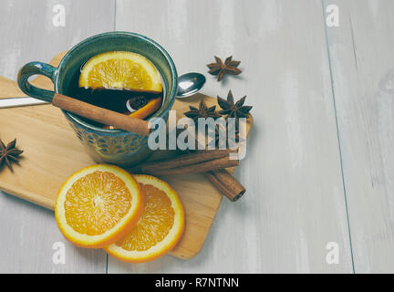 Una tazza di ceramica di riscaldamento tè con cannella e arancio su un rustico tavolo bianco. copia spazio. vista verticale .. Foto Stock