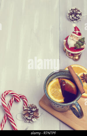 Una tazza di ceramica di riscaldamento tè con cannella e arancio su un rustico tavolo bianco. copia spazio. vista dall'alto. Foto Stock