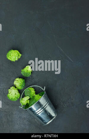 Placer broccoli verdi segmenti da un piccolo cucchiaio. Mangiare sano pattern su sfondo scuro. Spazio Copia vista dall'alto. Cibo vegetariano. Foto Stock