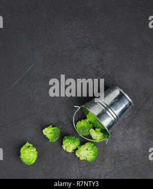 Placer broccoli verdi segmenti da un piccolo cucchiaio. Mangiare sano pattern su sfondo scuro. Spazio Copia vista dall'alto. Cibo vegetariano. Foto Stock