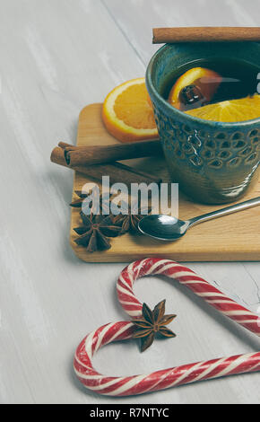 Una tazza di ceramica di riscaldamento tè con cannella e arancio su un rustico tavolo bianco. copia spazio. vista verticale .. Foto Stock