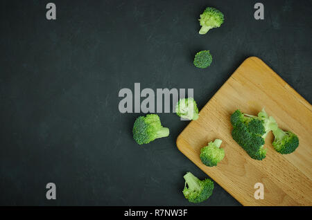 Placer broccoli verdi segmenti da un piccolo cucchiaio. Mangiare sano pattern su sfondo scuro. Spazio Copia vista dall'alto. Cibo vegetariano. Foto Stock