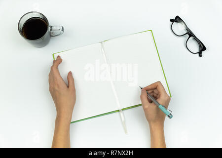 La creazione di nuove idee concetto. Vista dall'alto di mani femminili iscritto in una copia di un libro sul tavolo bianco Foto Stock