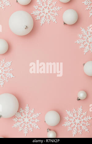 Festosa composizione d'inverno. Bianco palle di Natale e fiocchi di neve su un pastello sfondo rosa Foto Stock