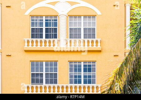 Condomini, condomini coloratissimi, giallo arancio dipinto facciata di edificio esterno con windows, Palm tree, mansion immobiliare di proprietà in Florida o Spai Foto Stock
