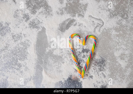 Candy canes disposti in una forma di cuore contro uno sfondo bianco per convogliare il concetto di san valentino.colorata lollipop.Candy valentines cuori.colorata natale candy canes. Biglietto di auguri.spazio copia Foto Stock