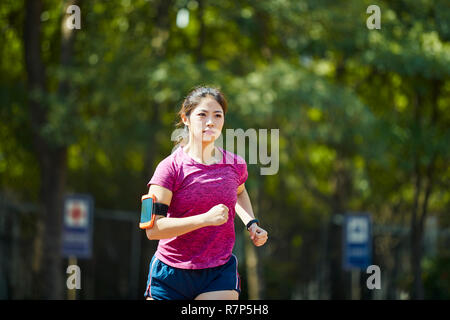 Giovane donna asiatica via e un campo sportivo in esecuzione Foto Stock