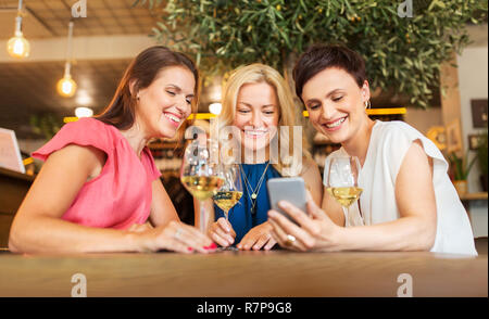 Le donne con lo smartphone a wine bar o ristorante Foto Stock