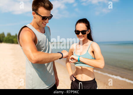 Coppia felice con fitness tracker sulla spiaggia di estate Foto Stock