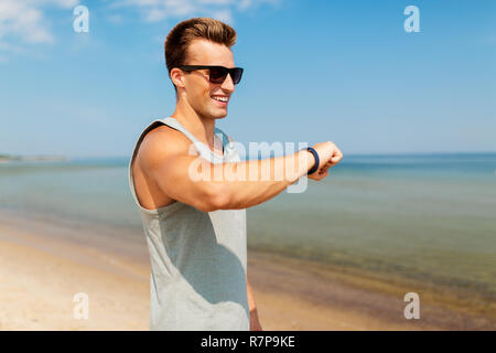 Uomo felice con tracker di fitness sulla spiaggia di estate Foto Stock