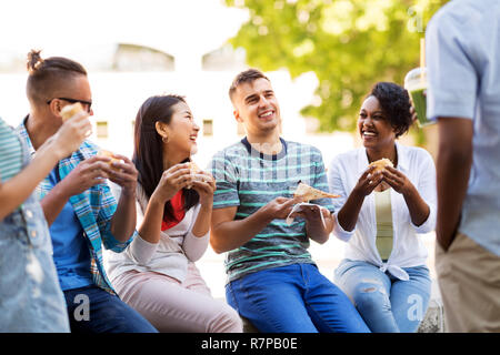 Gli amici di mangiare pizza e tramezzini in posizione di parcheggio Foto Stock