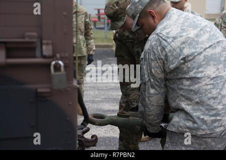 Due soldati da HHC 416th TEC sollevare e tenere una barra di traino, come un M1165 A1 tira fuori da sotto. Operazioni di recupero della formazione consente ai soldati di acquisire una comprensione di come recuperare un rotto-down, veicolo in un ambiente controllato. Operazioni di recupero è stata parte del curriculum insegnate durante HHC week-long conducente corso di formazione Foto Stock