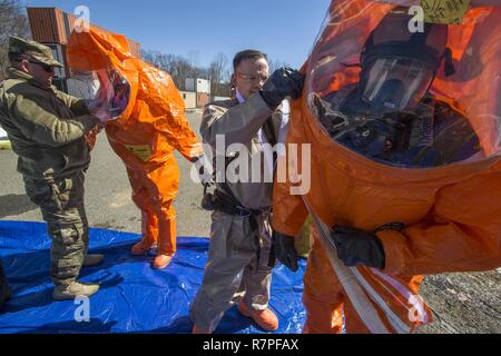 New Jersey Guardia Nazionale della ventunesima armi di distruzione di massa supporto Destruction-Civil i membri del team Seconda Lt. Brandon Botley, sinistra, assiste Strike Team stati Sgt. Joe Bercovic, la seconda da sinistra, mentre il personale Sgt. Kenneth Williams, secondo da destra, zips Strike Team membro Staff Sgt. Nicky Lam al livello di una tuta protettiva durante un esercizio di formazione con la Picatinny Arsenal dei Vigili del fuoco presso il New Jersey Homeland Defence Homeland Security Center a Picatinny Arsenal, N.J., Marzo 23, 2017. Il ventunesimo WMD-CST è una unità di snodo compreso del New Jersey e la Guardia Nazionale di soldati e aviatori la cui missione è di sostenere Foto Stock