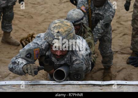 Un U.S. Soldato, assegnato alla sanità pubblica in Europa di Comando, sposta il suo corpo attraverso un polo per ottenere su di un ostacolo durante un team-building evento al settimo Esercito di formazione del comando di Grafenwoehr area formazione Germania, 20 marzo 2017. Il team-building esercizi, che incluse fisica e intellettuale, le funzioni sono state progettate per la costruzione di unità morale e cameratismo tra i team. Foto Stock