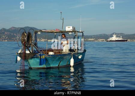 Francia, Alpes Maritimes, Cannes, pescatore indietro è netto sulla sua barca nella baia di Cannes Foto Stock