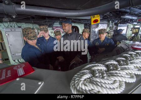 Mare delle Filippine (28 marzo 2017) Boatswain compagno del marinaio Ahmed Jamjalloh, centro da Alexandria, Virginia, spiega il ruolo del timoniere di Marines, assegnato al trentunesimo Marine Expeditionary Unit (MEU), sul ponte dell'assalto anfibio nave USS Bonhomme Richard (LHD 6). Bonhomme Richard, ammiraglia del Bonhomme Richard Expeditionary Strike gruppo, con avviato 31 Marine Expeditionary Unit, è su una pattuglia di routine, operando in Indo-Asia-regione del Pacifico per migliorare la prontezza combattimento e la postura in avanti come una pronta risposta in vigore per qualsiasi tipo di emergenza. Foto Stock