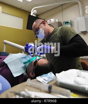 Navy Lt. La Cmdr. Jason Allen attaccato al Marine 4° Battaglione dentale a cura di artico 2017 esegue un canale della radice come parte della preparazione innovativo programma di formazione Marzo 27, 2017, Kodiak, Alaska. ARCTIC CARE 2017 è un civile-militare intesa di collaborazione per costruire su basi reciprocamente vantaggiose partenariati tra comunità degli Stati Uniti e del Dipartimento della Difesa. Esso fornisce opportunità di formazione per i militari USA (attivo, Guardia, riserva) e Canadian Health service i membri a prepararsi per la distribuzione in tutto il mondo sostenendo nel contempo le esigenze della comunità meno servite sull isola di Kodiak, Alaska. Foto Stock