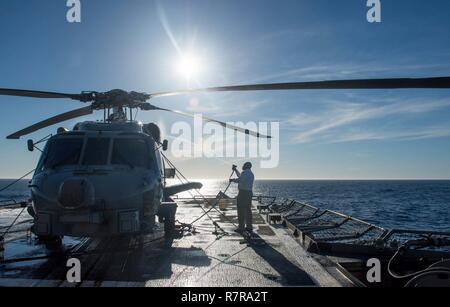 Oceano Pacifico (29 marzo 2017) il capo di aviazione del macchinista Mate Xavier Lewis, da Houston, pulisce un MH-60R Sea Hawk elicottero assegnato al "Wolfpack' di elicottero Maritime Strike Squadron (HSM) 75 a bordo della Ticonderoga-class guidato-missili cruiser USS Princeton (CG 59) mentre è in corso di realizzazione per un composito unità di addestramento esercizio (COMPTUEX) con il vettore Nimitz Strike gruppo in preparazione per una prossima distribuzione. Prove COMPTUEX la missione disponibilità dello sciopero del gruppo attività attraverso la simulazione di scenari del mondo reale e la loro capacità di eseguire come una unità integrata. Foto Stock