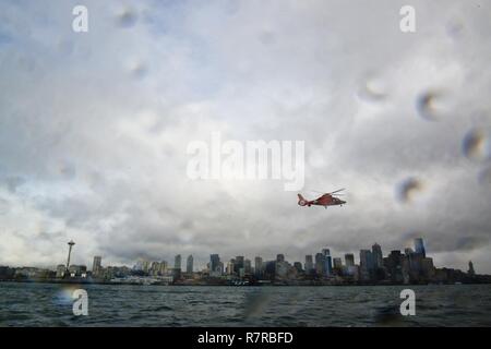 Un MH-65 Delfino elicottero dalla guardia costiera Stazione aria Port Angeles vola attraverso la skyline di Seattle Mar. 29, 2017. L'elicottero è stato nell'area di Seattle mentre il guardacoste Munro era tirando in porta per la Munro la cerimonia di messa in servizio il sabato. Stati Uniti Coast Guard Foto Stock