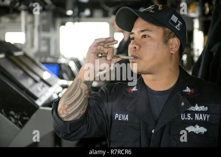 Stati Uniti 7TH FLOTTA AREA DI OPERAZIONI (25 marzo 2017) di Boatswain Mate 2a classe Marte Peña, dal Bronx, New York, tubi di inizio di chow oltre i 1MC annunciando il sistema dal ponte di Ticonderoga-class guidato-missili cruiser USS Lake Champlain (CG 57). Lake Champlain è su un regolarmente programmati Pacifico occidentale di implementazione con la Carl Vinson Carrier Strike gruppo come parte dell'U.S. Flotta del pacifico-led iniziativa di estendere il comando e le funzioni di controllo di Stati Uniti 3a flotta del Indo-Asia-regione del Pacifico. Navy portaerei strike gruppi hanno pattugliato il Indo-Asia-Pacifico regolarmente un Foto Stock